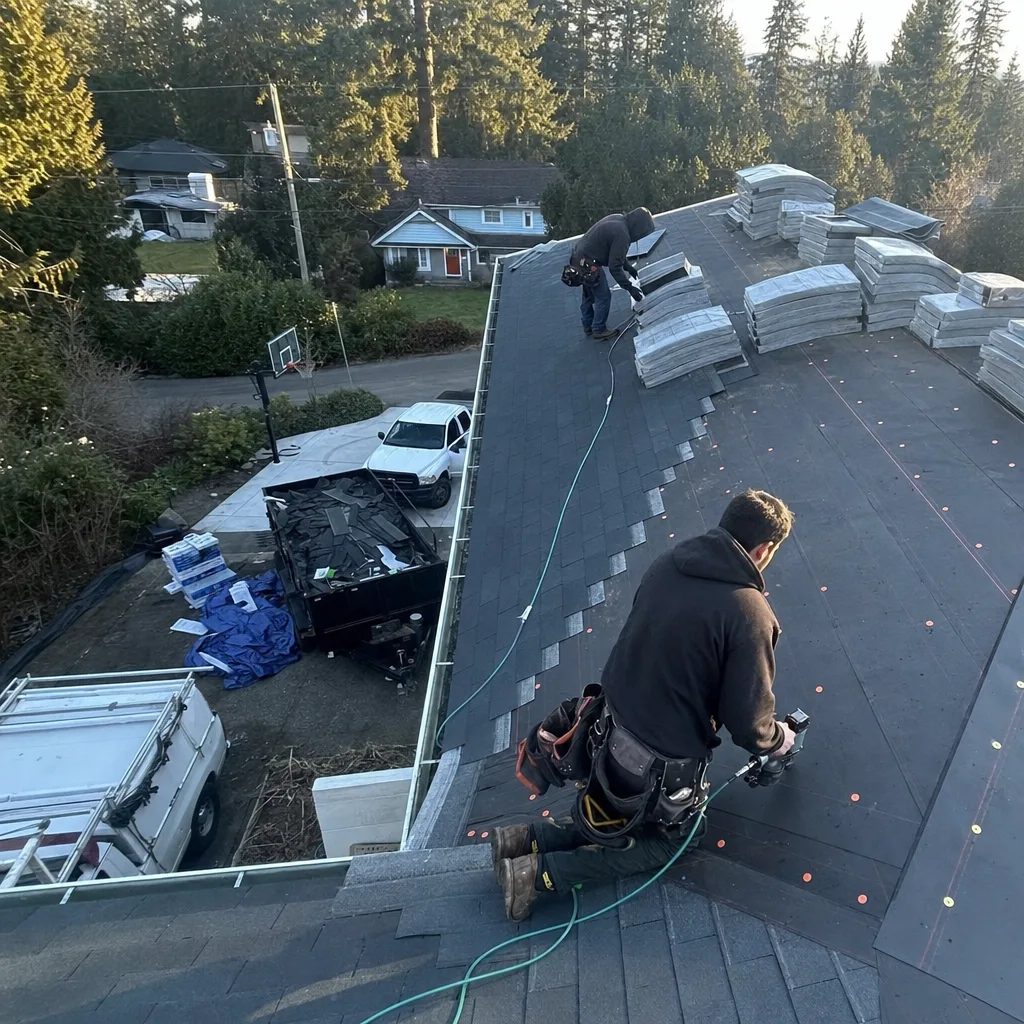 Two professional roofers installing new shingles during a roof replacement